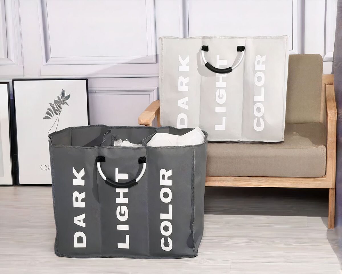 Panier à linge compartimenté en tissu On voit deux paniers à linge en tissu un gris foncé, une gris clair. Dans une salle de bain. Machine à laver.