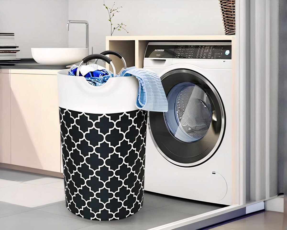 On voit un panier à linge en tissu avec des poignées. Il est grand, cylindrique avec des motifs graphiques designs.