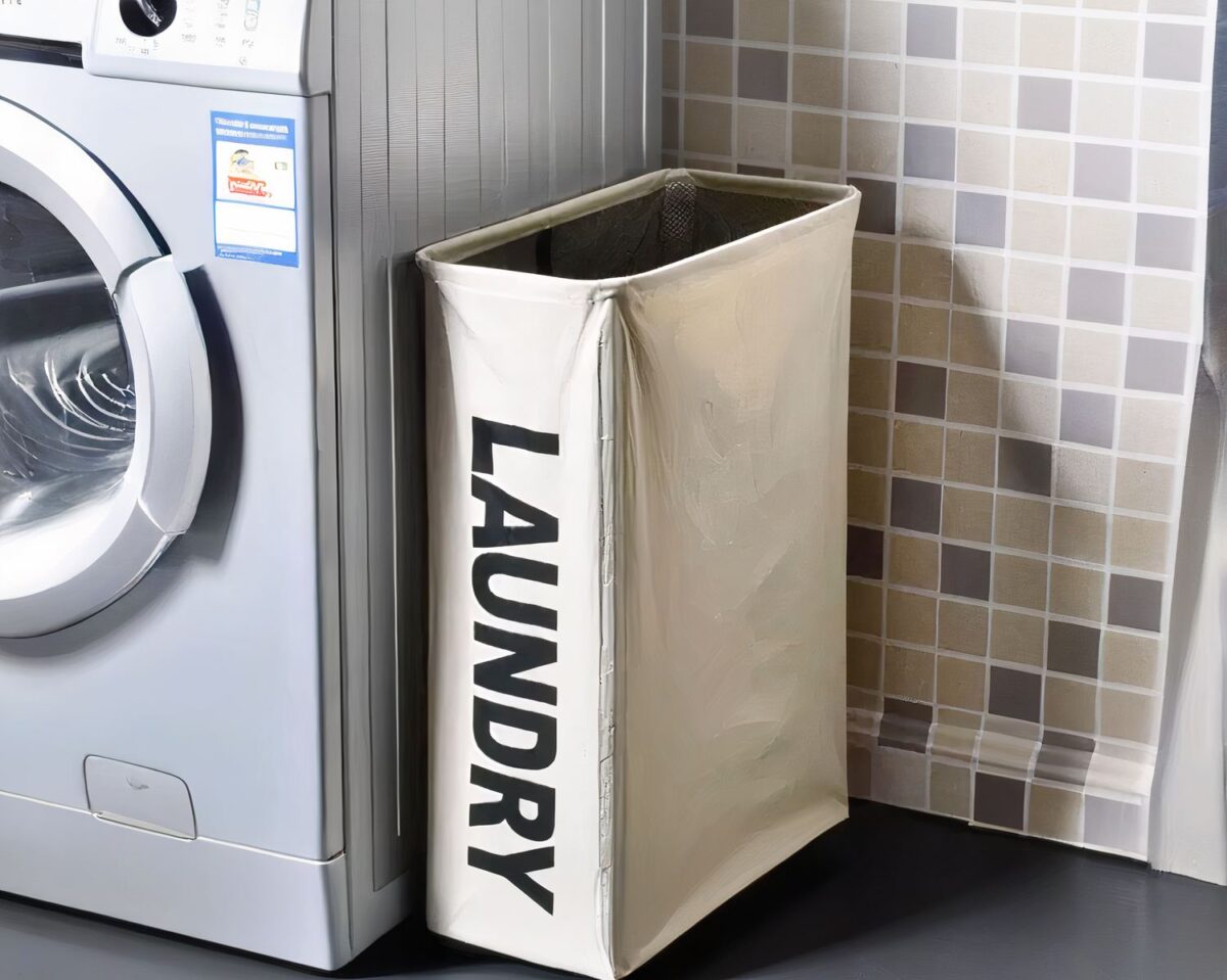 On voit un panier à linge écru sur lequel est marqué "Laundry" à côté d'une machine à laver
