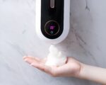 On voit une main qu ise sert en savon sous un distributeur de savon automatique mural avec affichage de la température en numérique