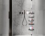 Photo d'un poteau réglable en hauteur portant cinq étagères de douche d'angle noire en plastique avec rebord et crochets le tout dans une douche moderne aux murs gris foncé