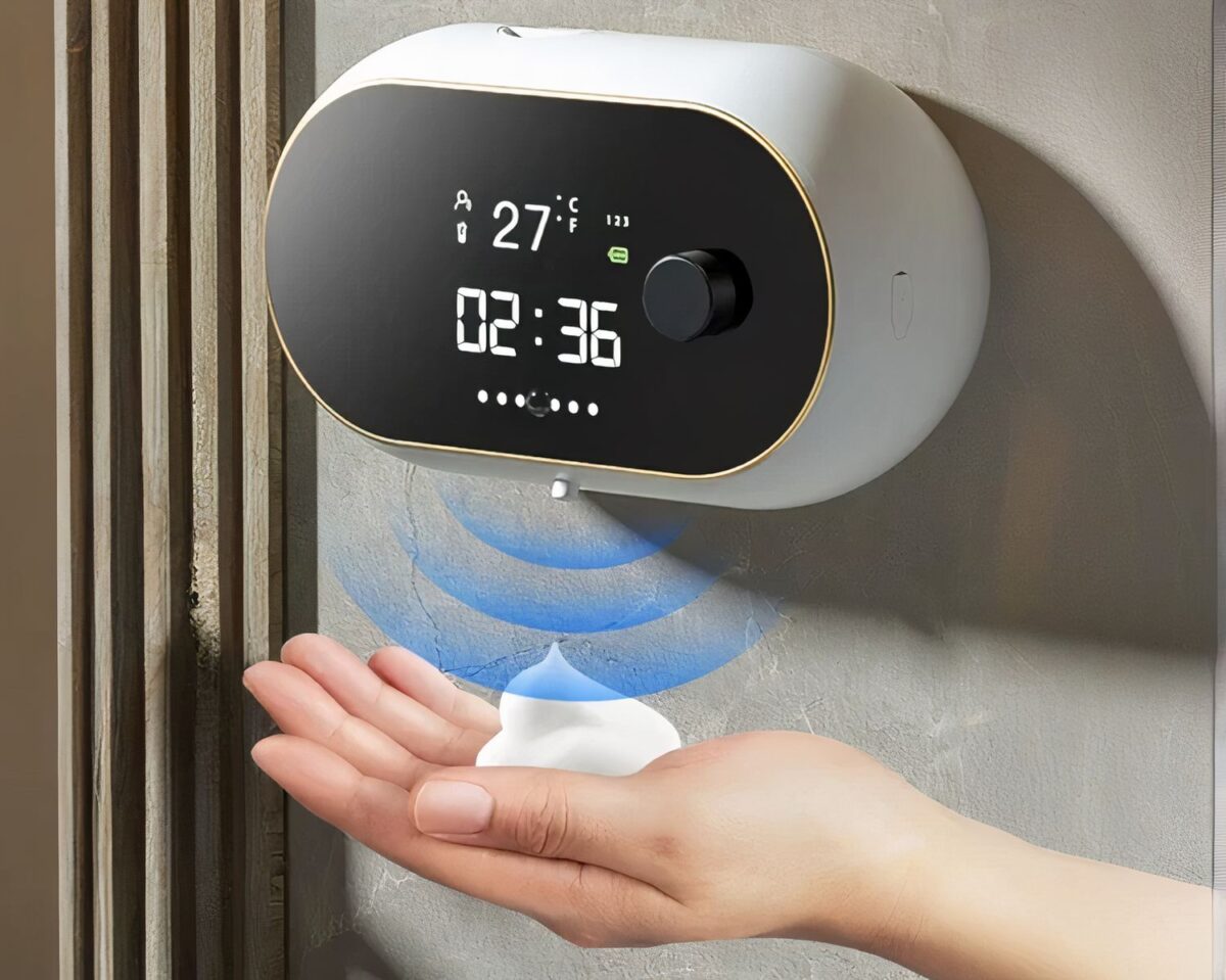 Personne se servant d'un distributeur de savon avec horloge.