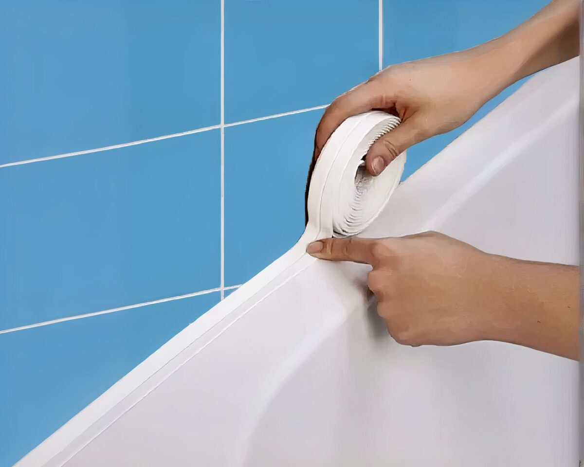 Joint de salle de bain en bande autocollante Pose d'un joint blanc le long d'une baignoire et d'un mur en carrelage bleu