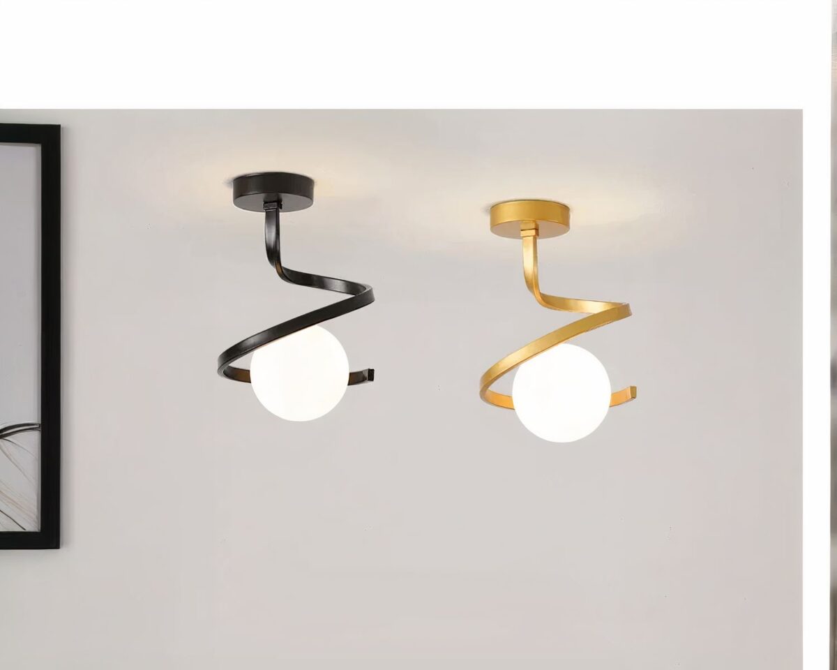 Photo de deux luminaires de salle de bain décoratifs modernes en forme de S l'un noir et l'autre doré avec un abat-jour boule de verre blanc sur un fond gris clair