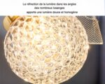 Photo d'un luminaire salle de bain doré en forme de fleurs à gros coeur et pétales légers transparents, le tout sur un fond gris foncé