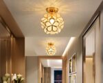 Photo de deux luminaires plafonniers polyvalents dorés en forme de fleur allumés dans un couloir aux tons beige sur un plafond beige