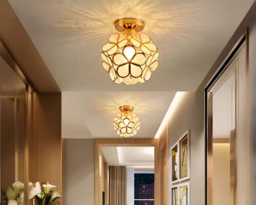 Photo de deux luminaires plafonniers polyvalents dorés en forme de fleur allumés dans un couloir aux tons beige sur un plafond beige