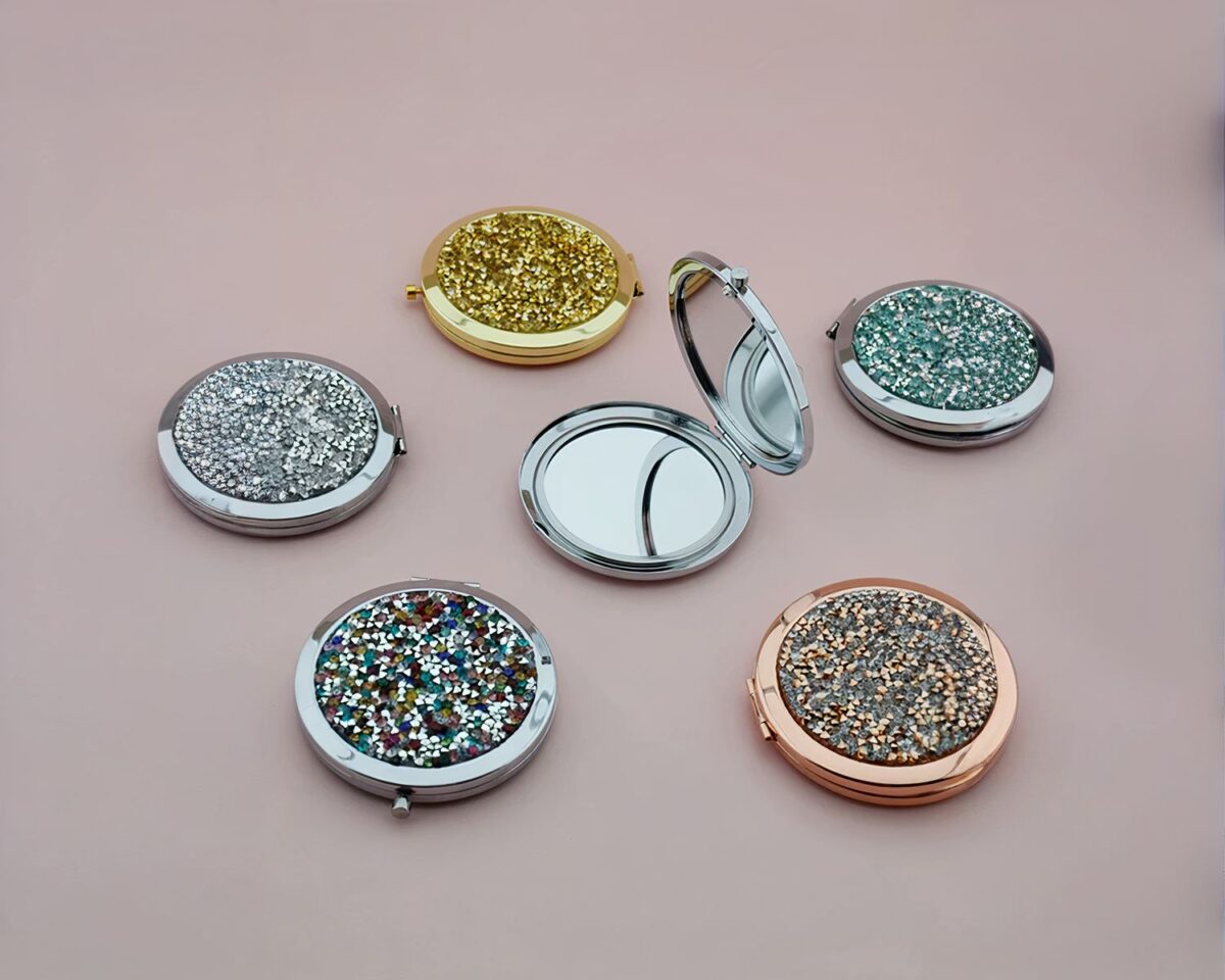 Miroirs de poche à paillettes sur fond rose.