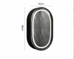 Miroir ovale sur un mur gris.