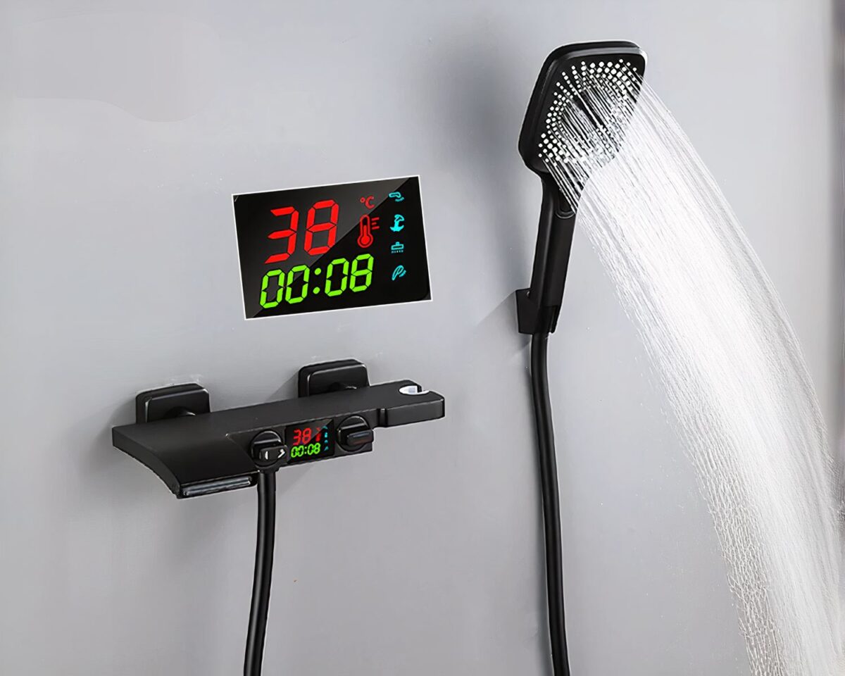 Photo d'un mitigeur de salle de bain noir à affichage numérique, le pommeau de douche ouvert le tout sur un mur gris