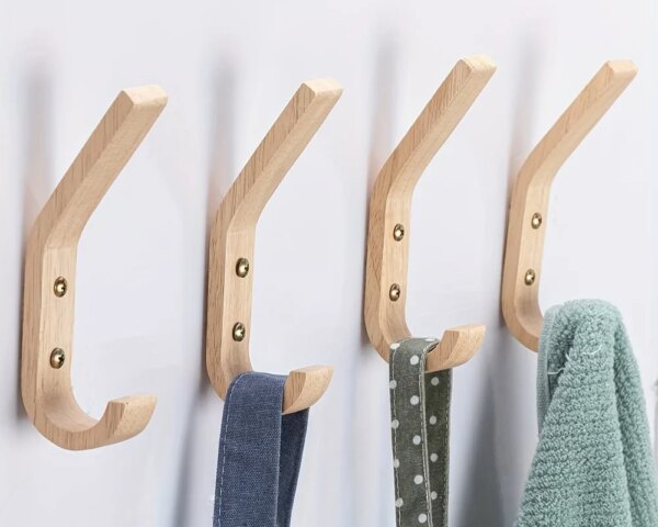 4 patères en bois clair accrochés au mur avec des objets accroches dessus