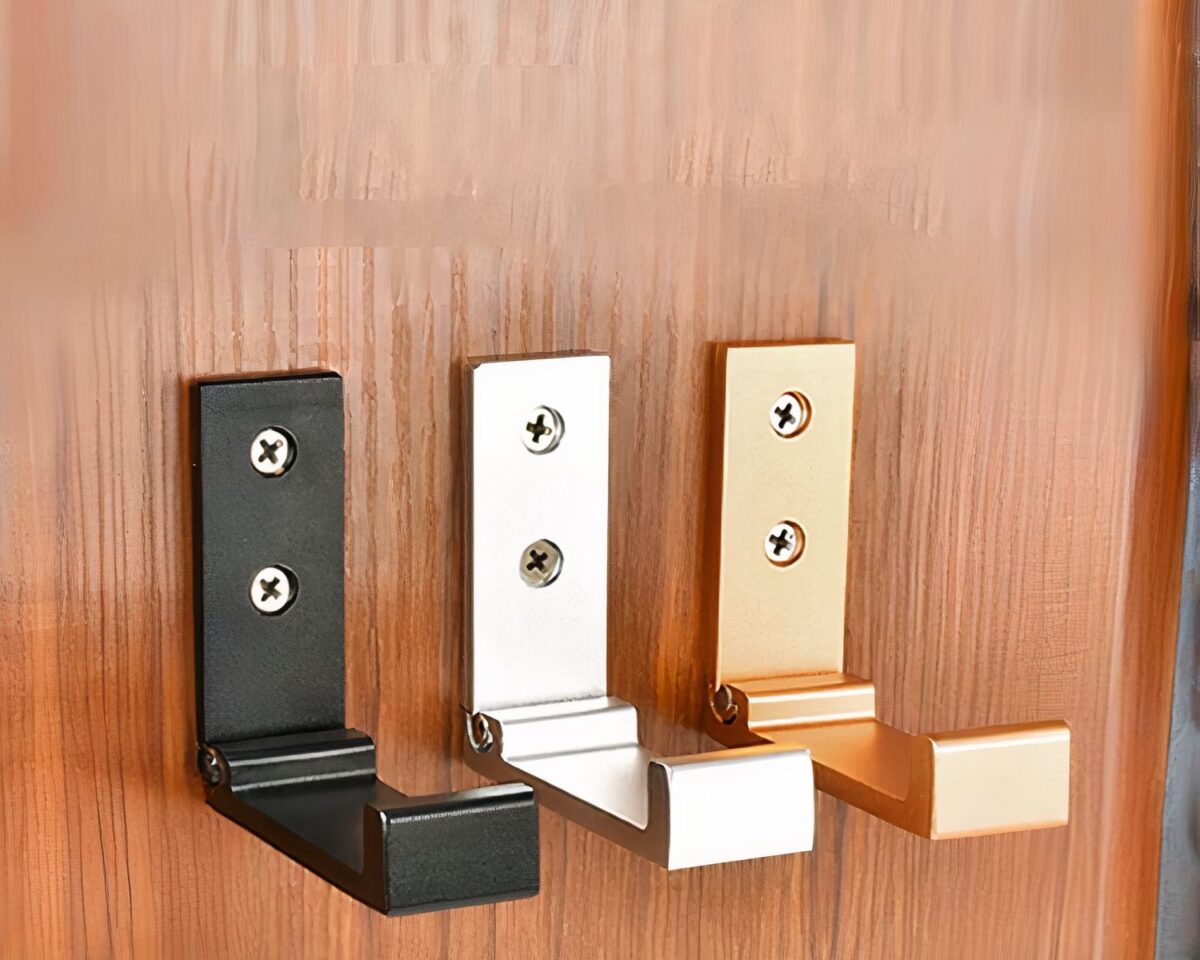 Une patère noire, une patère argentée et une patère dorée accrochées au mur