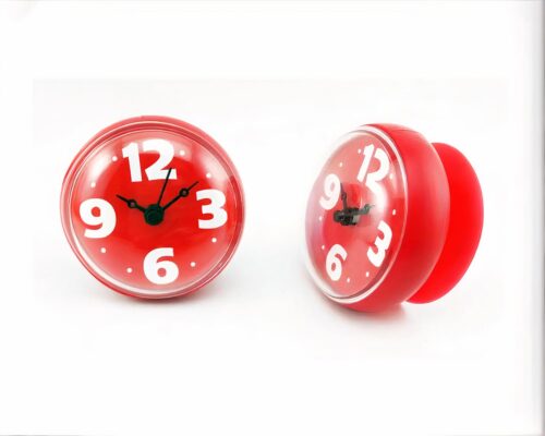 On voit des petites horloges colorées posées sur un meuble en bois.