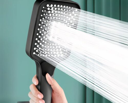On voit un pommeau de douche noir duquel sort un jet d'eau haute pression