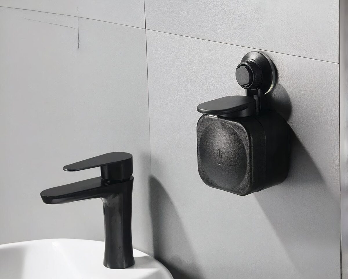 On voit un distributeur de savon mural à ventouse noir