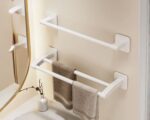 On voit deux porte-serviettes blanc : un avec une barre simple, l'autre avec deux barres. Ils sont installés au mur près d'un miroir.