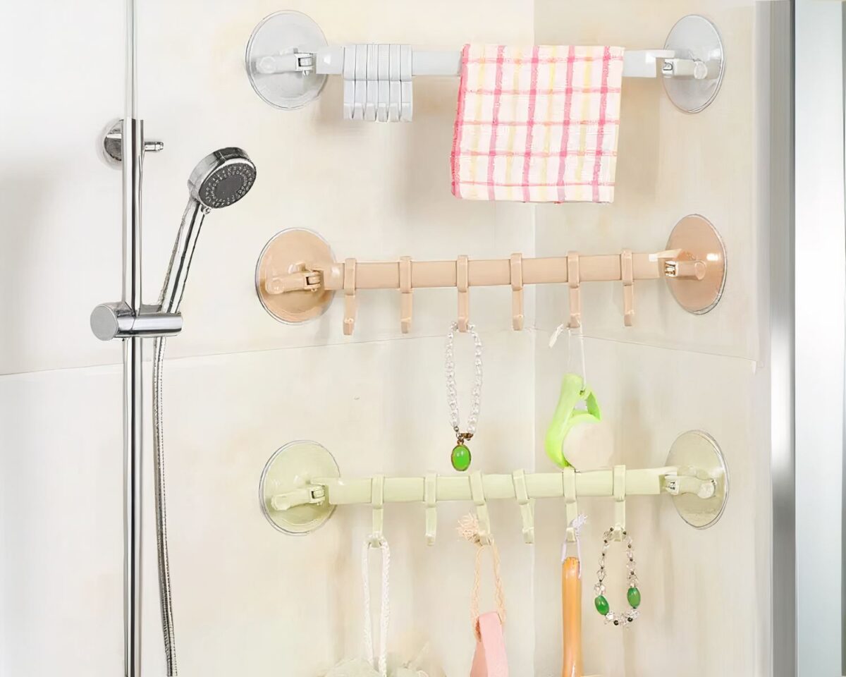 On voit trois porte-serviettes aux couleurs pastel qui ornent la faïence d'une douche.