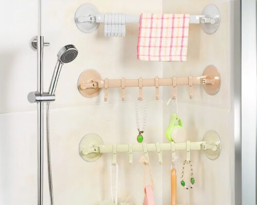 On voit trois porte-serviettes aux couleurs pastel qui ornent la faïence d'une douche.