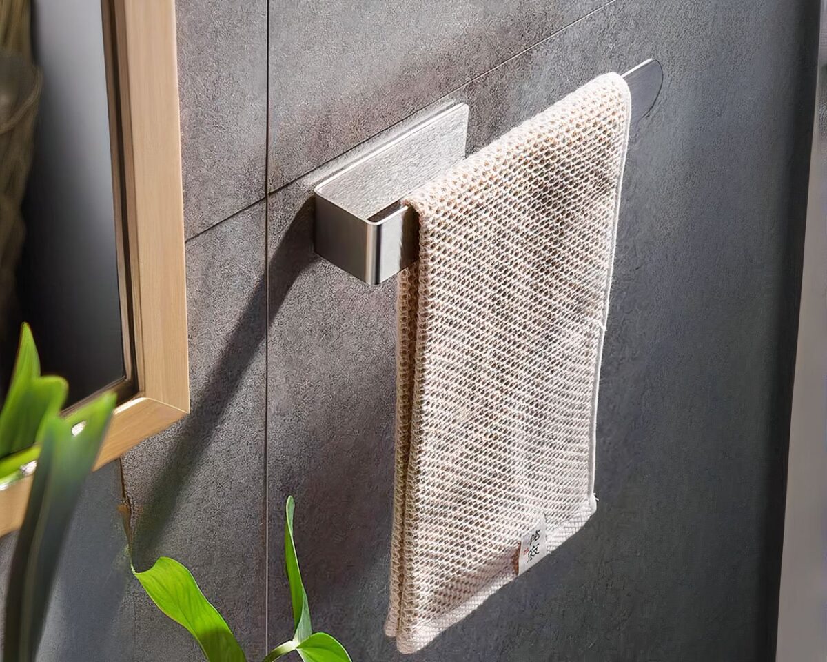 On voit un porte serviette mural, sur un mur effet marre, qui soutient une serviette beige.