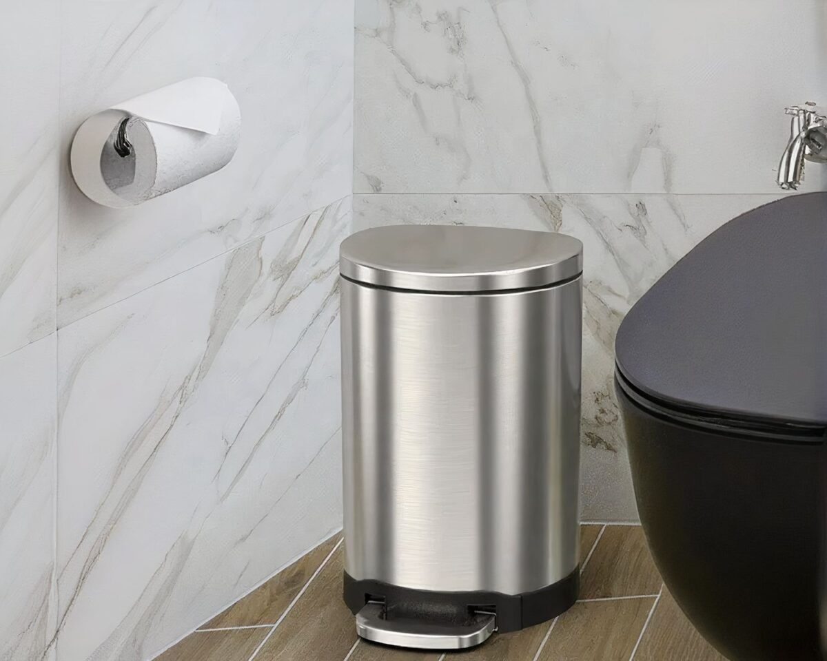 Photo d'une poubelle de salle de bain semi-ronde argentée à pédale dans un cabinet de toilette aux murs marbrés gris