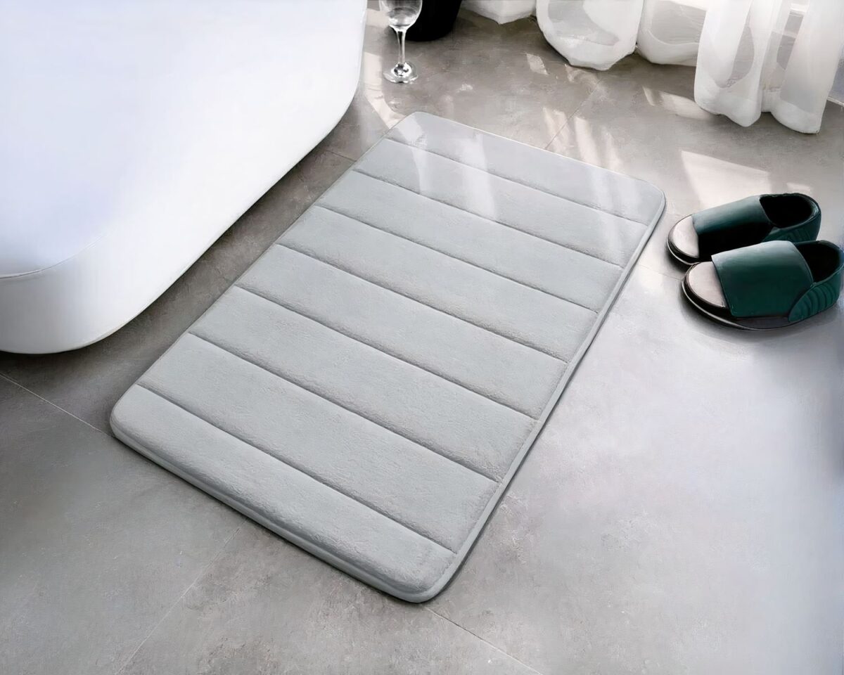 Tapis gris avec des rayures devant une baignoire.